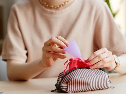 Una mujer guardando una copa menstrual dentro de su bolsa de transporte.