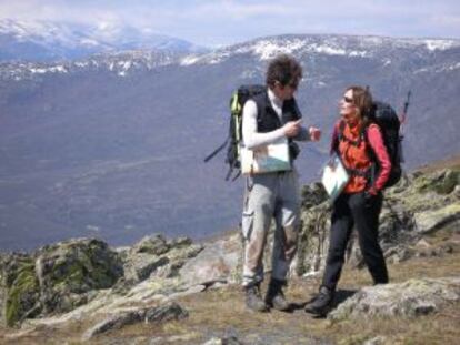 Dos excursionistas, con el Pico del Lobo, en la sierra de Ayllón, al fondo.