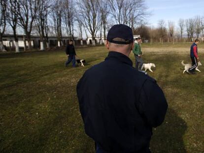 Un policía controla a los prisioneros durante su paseo con perros.