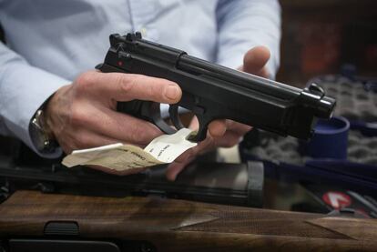 Gun-seller Carlos López handles a pistol.