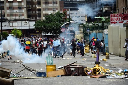 Una multitud corre por una avenida bloqueada con barricadas durante los enfrentamientos con la policía.