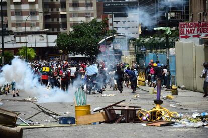 Una multitud corre por una avenida bloqueada con barricadas durante los enfrentamientos con la policía.