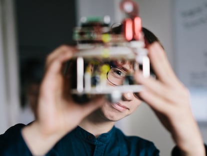 Un adolescente analiza un robot electrónico casero.