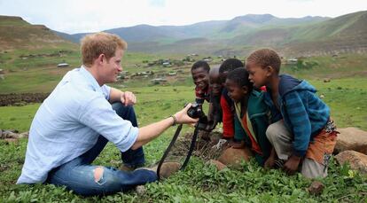 El príncipe Enrique de Inglaterra juega con unos niños y una cámara de fotos en una visita a una escuela construida en Mokhotlong, Lesotho gracias a su ONG Sentebale, el 8 de diciembre de 2014.