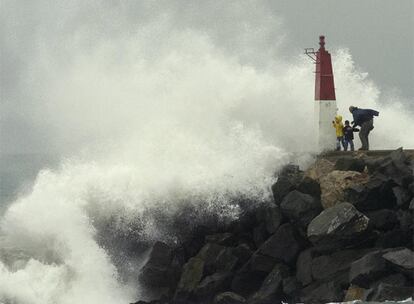 Arriba, pasajeros de un tren de media distancia evacuados en Torredembarra. Abajo, una familia observa el rompeolas, a la entrada del puerto de Empuriabrava, en Castelló d&#39;Empúries.
 / josep lluís sellart