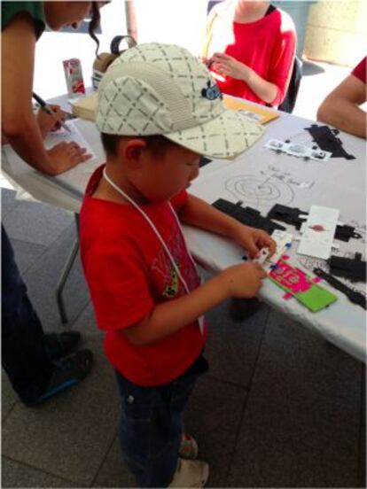 Un niño dobla las piezas que forman el microscopio de papel.