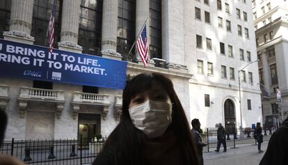 Una mujer con una mascarilla protectora contra el coronavirus frente a la sede del New York Stock Exchange. El miedo ante los estragos del coronavirus (Covid-19), llevaron a las Bolsas mundiales a registrar la peor sesión en lo que va de 2020. 