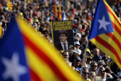 Un asistente muestra un cartel del 'expresident' de la Generalitat Carles Puigdemon con el lema "Persistimos y ganaremos". Los concentrados en Perpiñán portan banderas 'esteladas'.