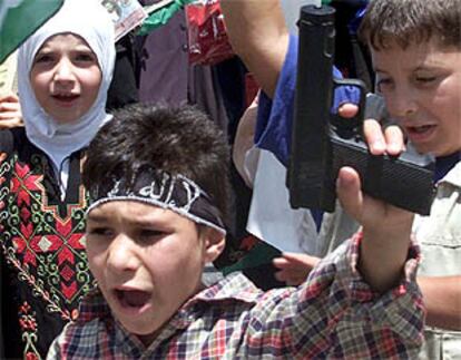 Un niño palestino sostiene una pistola de juguete durante un funeral en Hebrón.