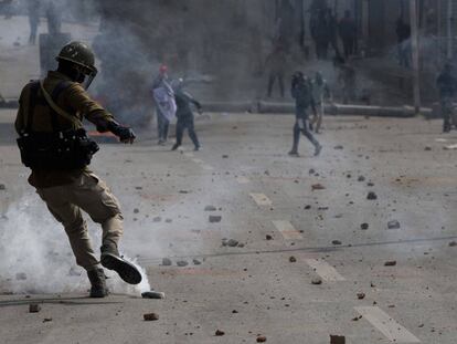 Un policía indio patea un proyectil de gas lacrimógeno lanzado por manifestantes, en Srinagar (India).