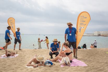 Dos informadores conversan de la nueva prohibición de fumar con bañistas, en la playa del Bogatell, Catalunya (España).