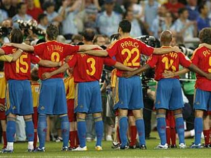 Los jugadores de la selección española de fútbol escuchan el himno nacional abrazados, antes de iniciar un partido.