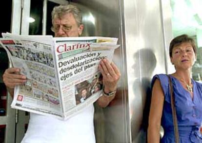 Un argentino lee un periódico mientras hace cola a las puertas de un banco de Buenos Aires.