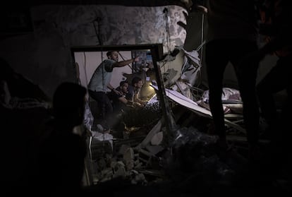 Palestinos buscan víctimas y supervivientes entre los escombros de un edificio residencial destruido tras un ataque israelí, este lunes en Jan Yunis.