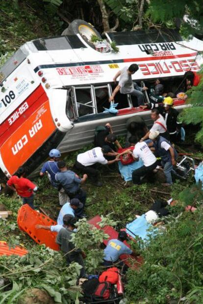 Miembros de los servicios de rescate portan un cuerpo después de que un autobús con 50 pasajeros se despeñara por un barranco