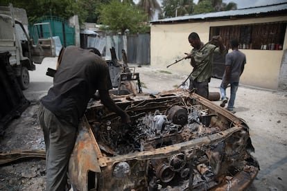 Un grupo de hombres trabaja para rescatar piezas de un automóvil que se incendió durante enfrentamientos entre bandas armadas en el barrio Butte Boyer, en Puerto Príncipe,  el 13 de mayo de 2022.