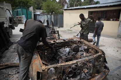 Un grupo de hombres trabaja para rescatar piezas de un automóvil que se incendió durante enfrentamientos entre bandas armadas en el barrio Butte Boyer, en Puerto Príncipe, el 13 de mayo de 2022.
