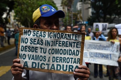 Un manifestante sostiene un cartel que dice "¡No seas ignorante! ¡No seas indiferente! Desde tu comodidad, no derrotaremos a la dictadura", durante la protesta opositora de este miércoles en Caracas.