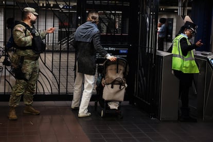 A member of the New York National Guard gestures to a subway rider at the 42nd Street station in the Times Square area of New York City, U.S., March 27, 2024.