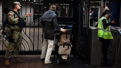 A member of the New York National Guard gestures to a subway rider at the 42nd Street station in the Times Square area of New York City, U.S., March 27, 2024.