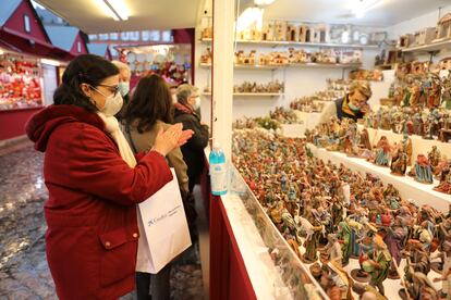 Una mujer se desinfecta las manos con gel hidroalcohólico en un puesto de belenes del mercadillo navideño de la Plaza Mayor, en Madrid.