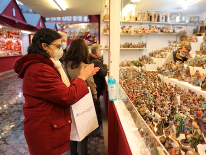 Una mujer se desinfecta las manos con gel hidroalcohólico en un puesto de belenes del mercadillo navideño de la Plaza Mayor, en Madrid.