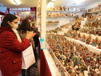 Una mujer se desinfecta las manos con gel hidroalcohólico en un puesto de belenes del mercadillo navideño de la Plaza Mayor, en Madrid.