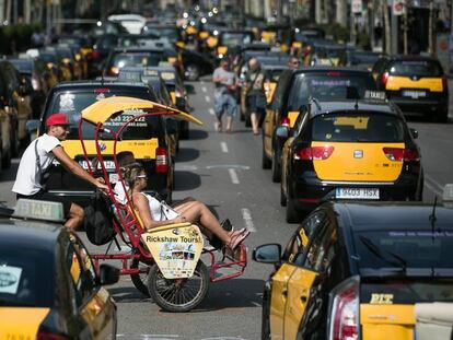 Un bici-taxi turístico cruza por la Gran Via de Barcelona, cortada por la huelga de taxistas