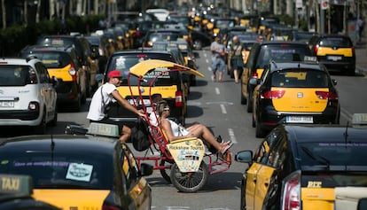 Un bicitaxi turístic creua per la Gran Via de Barcelona, tallada per la vaga de taxistes.