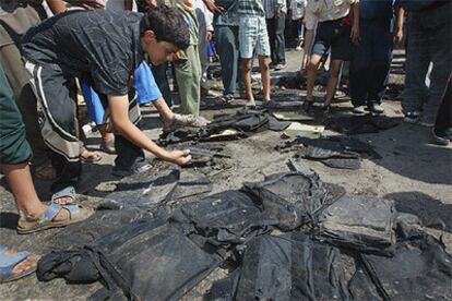Un grupo de iraquíes examina los chalecos antibala de los agentes que han sufrido uno de los atentados.