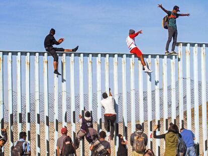 Integrantes de la caravana de centroamericanos escalan el muro fronterizo en Tijuana, en el estado de Baja California (México). 