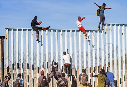 Integrantes de la caravana de centroamericanos escalan el muro fronterizo en Tijuana, en el estado de Baja California (México).
