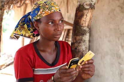 La joven Aisuto, con el teléfono móvil que le sirve para comprar comida, en el campo de refugiados de Lolo (Camerún).