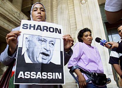 Una mujer palestina porta un cartel que llama asesino a Sharon frente al Palacio de Justicia de Bruselas.