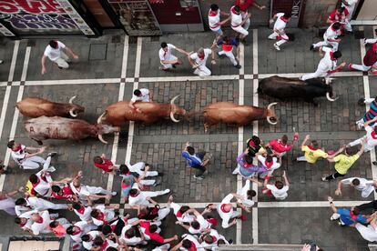 A group of runners alongside bulls from the Domingo Hernández ranch as they pass through Estafeta Street, this Thursday. 