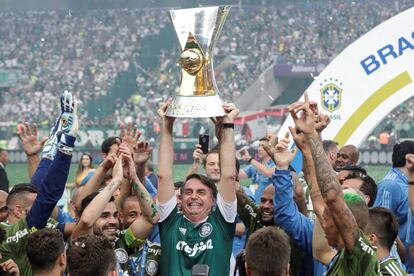 El presidente electo de Brasil, Jair Bolsonaro, levanta el trofeo junto a los jugadores de Palmeiras tras un partido del Campeonato Brasileño entre Palmeiras y Vitoria disputado en el estadio Allianz Parque, en Sao Paulo (Brasil).