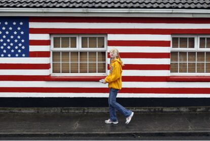 Una joven pasa ante una casa pintada con los colores de la bandera de EE UU, ayer en Moneygall (Irlanda), localidad que visitará Obama y en la que vivieron algunos de sus antepasados.