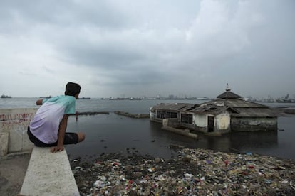 Joven mirando el mar después de las inundaciones en Jakarta. Abril 2017. Jakarta, Indonesia.