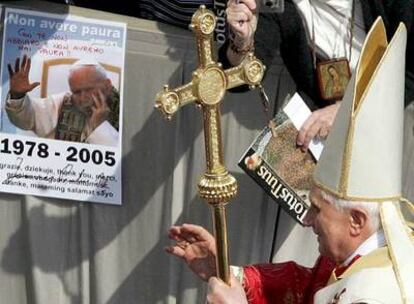 El papa Benedicto XVI saluda a los fieles delante de una pancarta con una imagen de su predecesor Juan Pablo II.