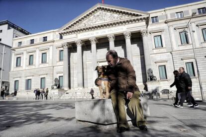 Un perro junto a su dueño ante el Congreso de los Diputados en Madrid (España), el 12 de diciembre de 2017.