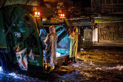 Los trabajadores de recogida de basura usan chubasqueros mientras recorren una calle inundada después de las fuertes lluvias en Bangkok (Tailandia), este miércoles.