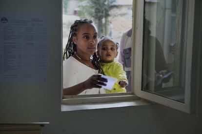 Una mujer entrega la tarjeta sanitaria que le debe dar derecho a recibir atención gratuita para su hija en el centro de salud de Afincho Ber (Adís Abeba, Etiopía).