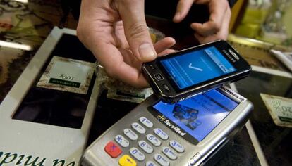 Una persona compra en un establecimiento con su teléfono móvil.