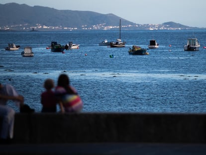 Una mujer observa con dos niñas la ría de Cee desde el paseo marítimo