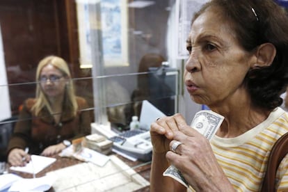 Una mujer venezolana porta billetes de un d&oacute;lar en Caracas.