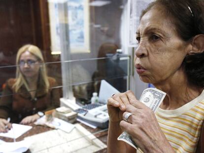 Una mujer venezolana porta billetes de un d&oacute;lar en Caracas.
