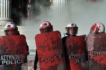 Policías antidisturbios manchados con pintura roja lanzada por los manifestantes después de una protesta en Atenas.