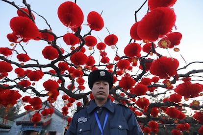 Un policía, rodeado de farolillos rojos, vigila el parque Ditan en Pekín durante las celebraciones del Año Nuevo chino.