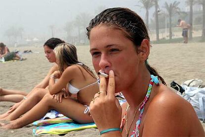 Una joven fumando ayer en la playa de la Malagueta (Málaga).