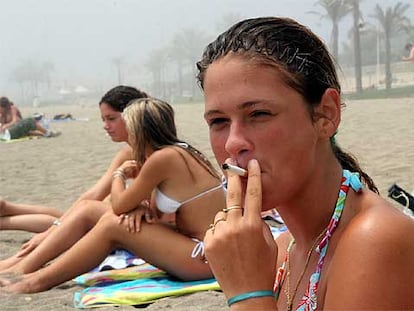 Una joven fumando ayer en la playa de la Malagueta (Málaga).